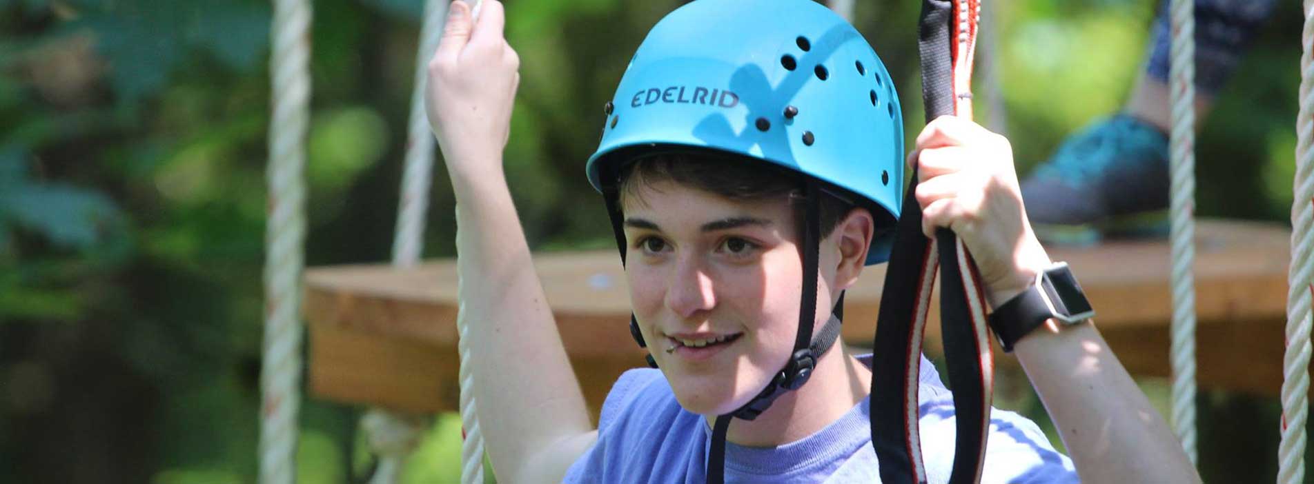 YMCA Camps Boy wearing helmet on rope obstacle course