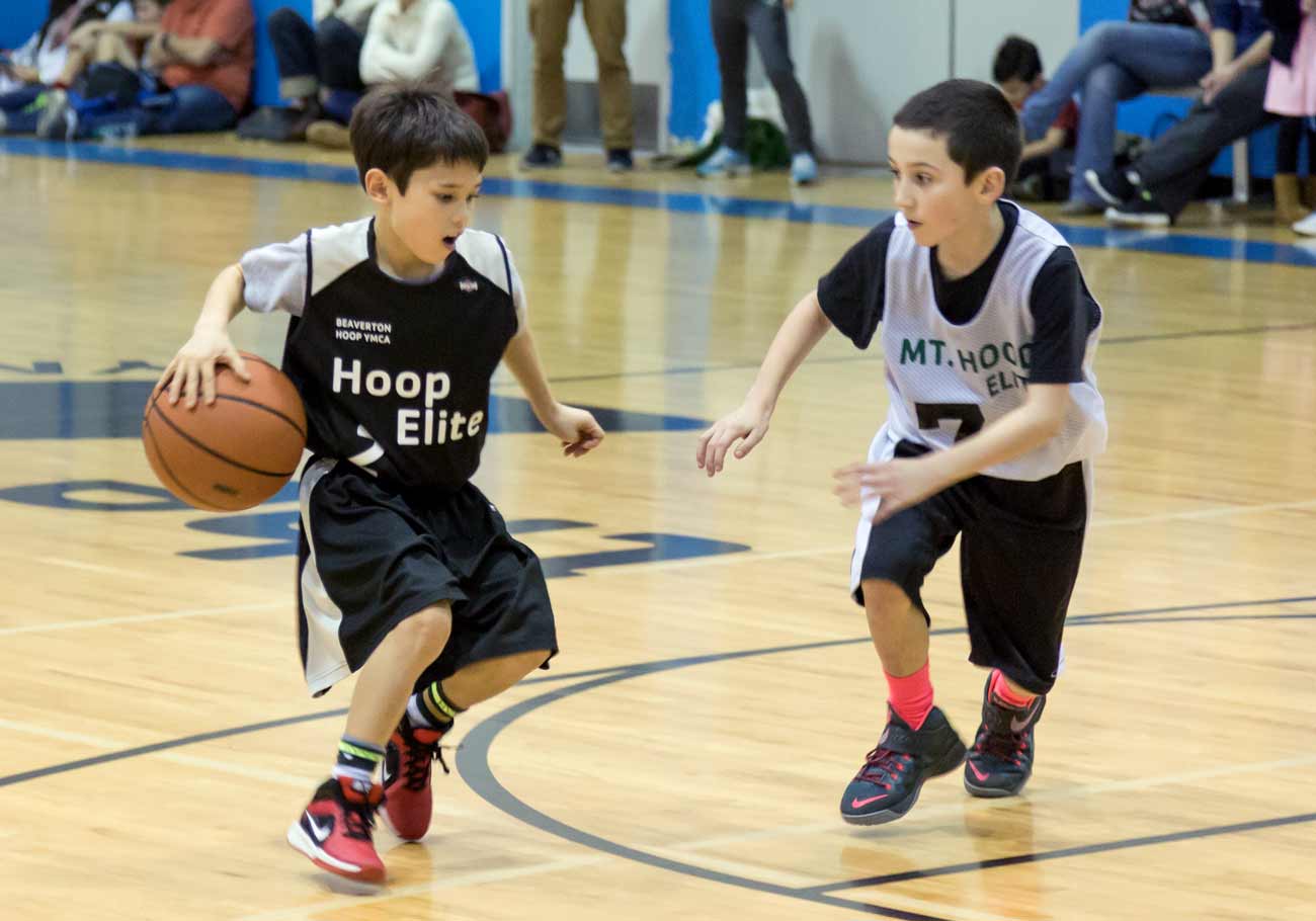 YMCA Youth Sports Two boys play basketball together in gym