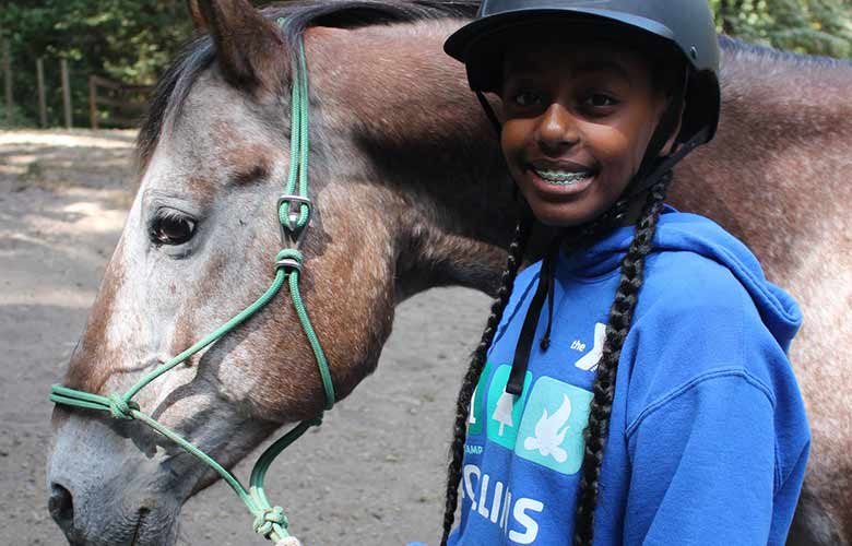 YMCA Overnight Camp Youth girl smiling with horse outside