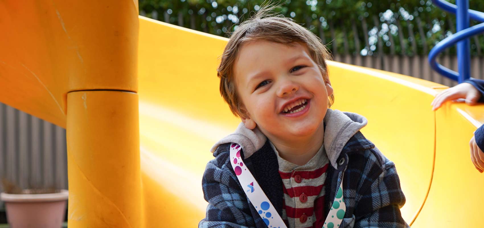 YMCA Youth Young boy smiles as he sits on slide at playground