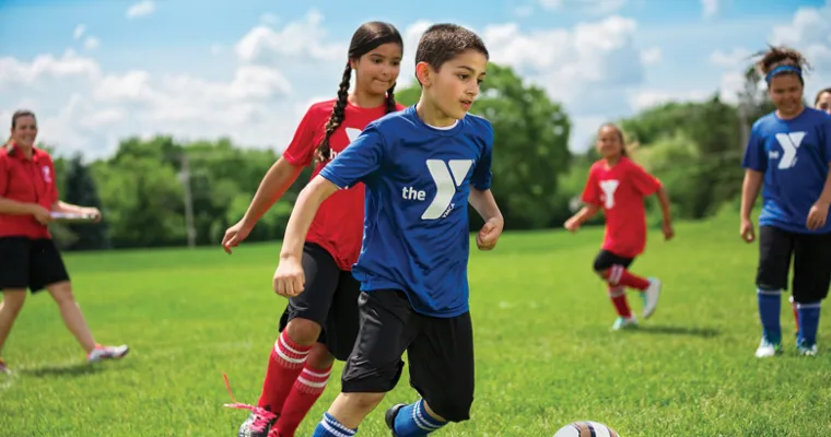 Young boys and girls playing soccer outdoors