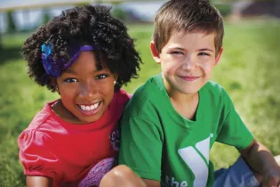 A boy and girl sit together in a field 